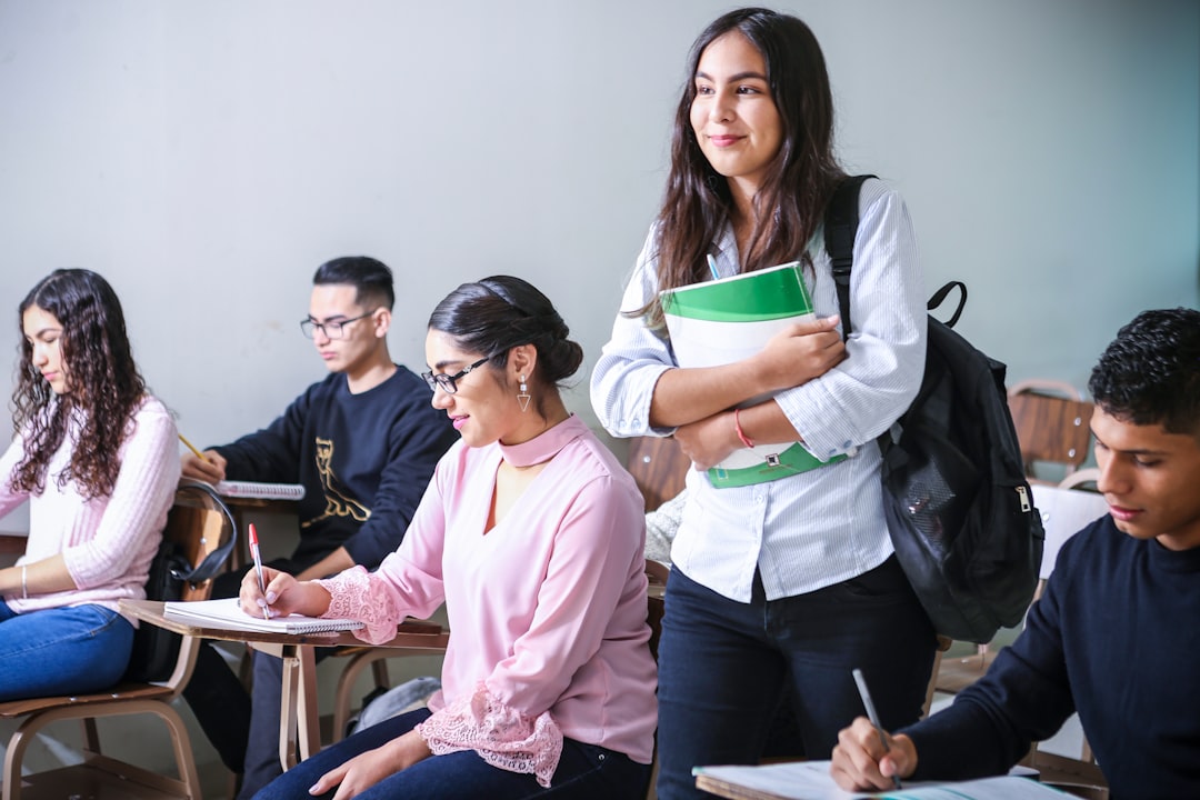 woman-carrying-white-and-green-textbook-iqpr1xkf5f0